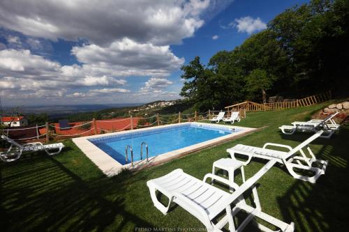 a swimming pool with two white chairs and a table at Casas do Pastor in Seia