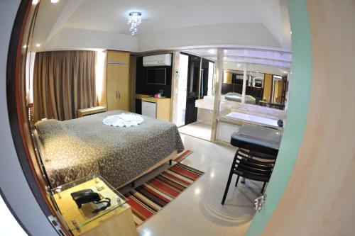 a bedroom with a bed and a desk and a kitchen at Hotel Premium Plaza in Muriaé