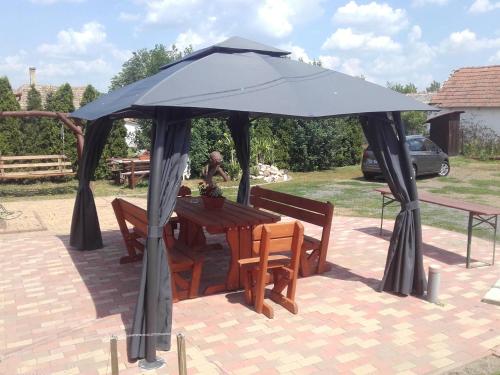 a picnic table with a large umbrella on a patio at Méz-Bor Szállás in Báránd