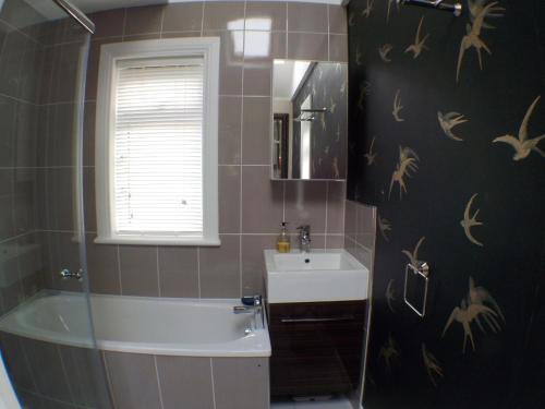 een badkamer met een wastafel, een bad en een toilet bij 16 Admiralty in Arrochar