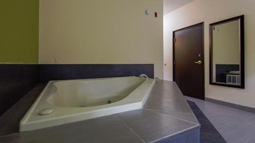 y baño con bañera grande y paredes verdes. en Best Western Plus Huntersville en Huntersville