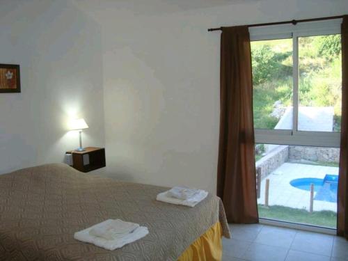 a bedroom with a bed and a window with a pool at Brisa Serrana in Potrero de los Funes