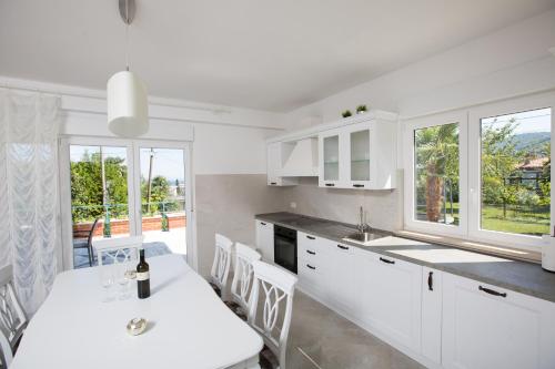 eine Küche mit weißen Schränken sowie einem Tisch und Stühlen in der Unterkunft Apartment Pepi in Lovran