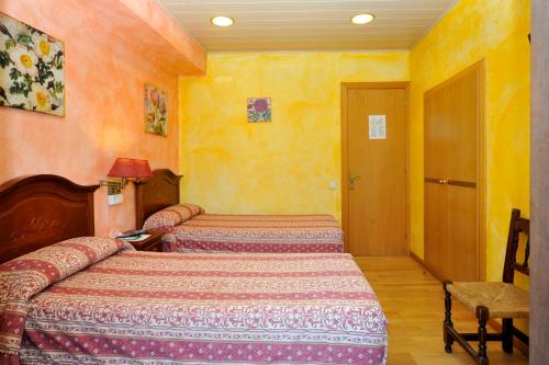 a bedroom with two beds in a room with yellow walls at Hostal Vall D'Aneu by Arcas & Sambola in Esterri d'Àneu