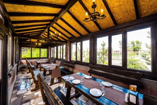 a restaurant with wooden tables and benches and windows at Adler in Astana
