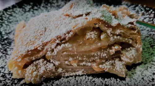 a piece of cake with powdered sugar on a plate at Hotel Flora in Bešeňová
