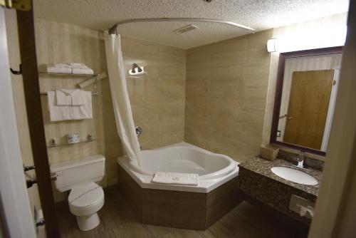 a bathroom with a tub and a toilet and a sink at Tropical Inn - North Battleford in North Battleford