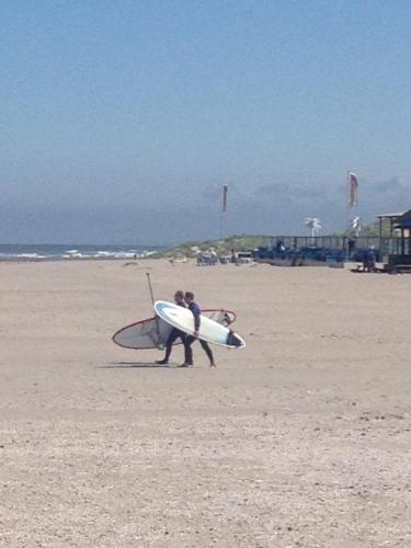 two people walking on the beach with their surfboards at B&B Habitat in Beverwijk
