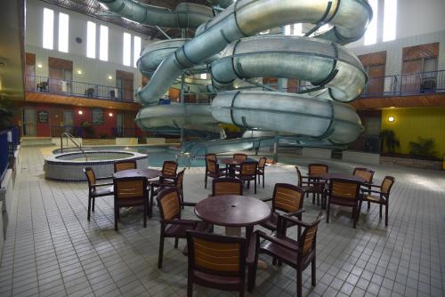 a restaurant with tables and chairs and a slide at Tropical Inn - North Battleford in North Battleford