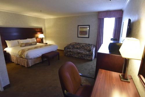 a hotel room with a bed and a chair at Tropical Inn - North Battleford in North Battleford