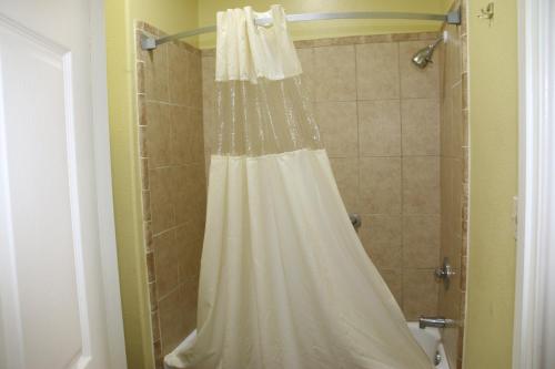 a shower with a white shower curtain in a bathroom at Ramada by Wyndham & Suites South Padre Island in South Padre Island