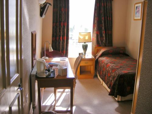 a hotel room with a bedroom with a bed and a desk at The Kings Head Hotel in Abergavenny