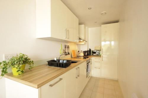 a kitchen with white cabinets and a wooden counter top at Marina Water View Apartment in Hull