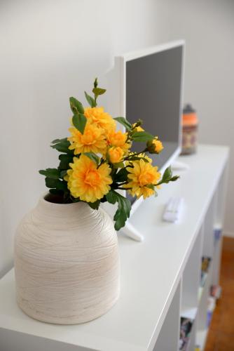 a bouquet of yellow flowers in a vase on a counter at Porto Smart Apartments- airport in Perafita