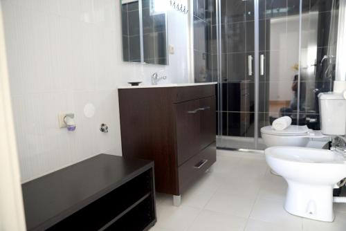 a bathroom with a toilet and a sink and a shower at Porto Smart Apartments- airport in Perafita