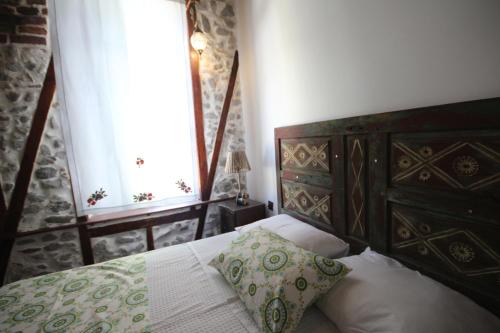 a bedroom with a bed with a wooden headboard and a window at TAŞKONAK in Bergama