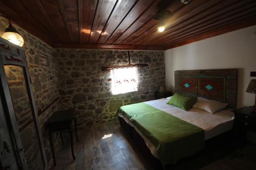 a bedroom with a green bed in a stone wall at TAŞKONAK in Bergama