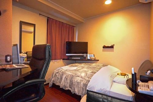 a hotel room with a bed and a desk with a computer at Hotel Satellite in Satsumasendai