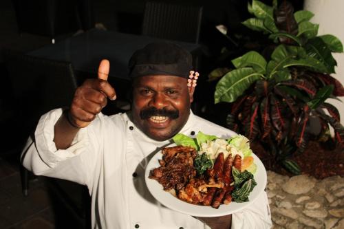 a man giving a thumbs up while holding a plate of food at The Melanesian Port Vila in Port Vila