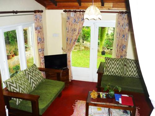 a living room with two green couches and a tv at Paradise Cottage Kandy in Kandy