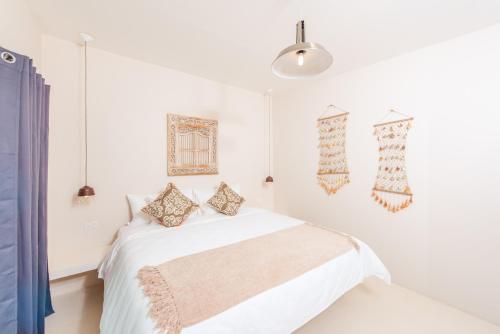 a white bedroom with a bed and a pendant light at La Ramona Charming Hotel in Tamarindo