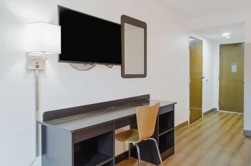 a desk with a television on a wall with a chair at Motel 6-Brockton, MA in Brockton