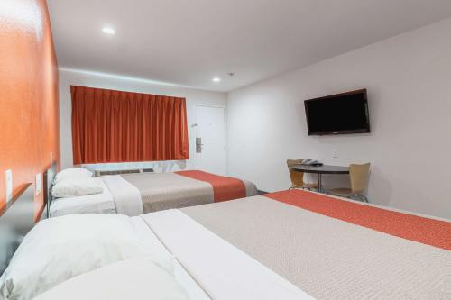 a hotel room with two beds and a table and a television at Motel 6-Barstow, CA - Route 66 in Barstow