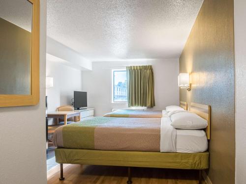 Mały pokój hotelowy z łóżkiem i biurkiem w obiekcie Studio 6-Miamisburg, OH - Dayton w mieście Miamisburg