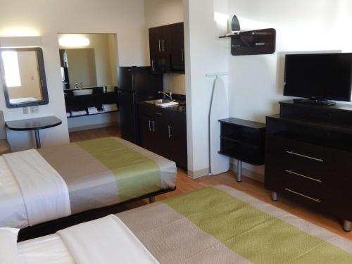 a hotel room with a bed and a flat screen tv at Studio 6-Yukon, OK in Yukon