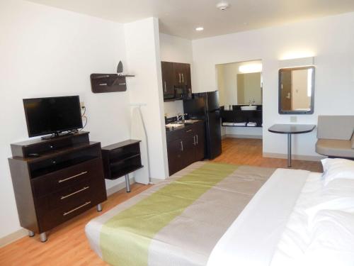 a bedroom with a bed with a television and a kitchen at Studio 6-Yukon, OK in Yukon