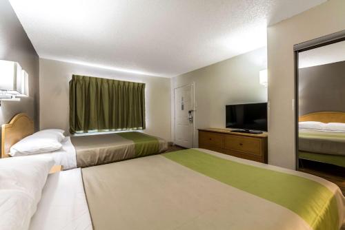 a hotel room with two beds and a flat screen tv at Studio 6-Dallas, TX - Northwest in Dallas