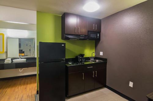 a kitchen with a black refrigerator and green walls at Studio 6-Tyler, TX in Tyler
