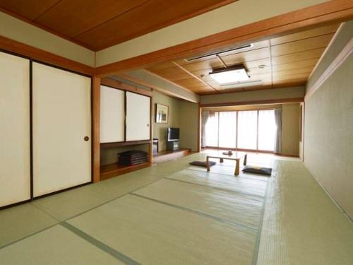 an empty room with a room with a table in it at Hotel Suimeikan in Yamanouchi