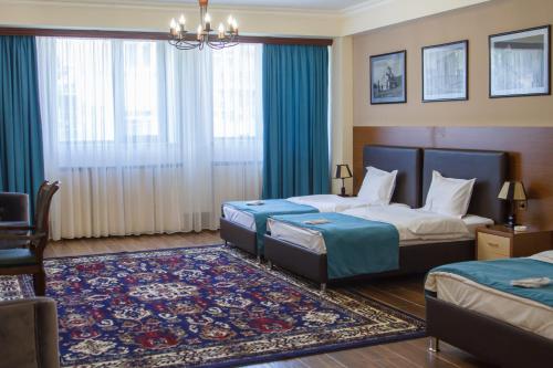 a hotel room with two beds and a rug at Hotel Plaza Viktoria in Gyumri