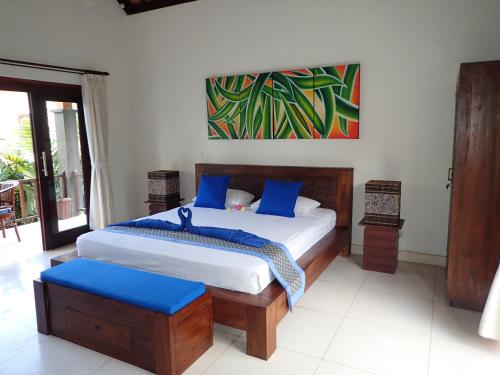 um quarto com uma cama grande e almofadas azuis em Alami Resort, Restaurant and Dive Center em Amed
