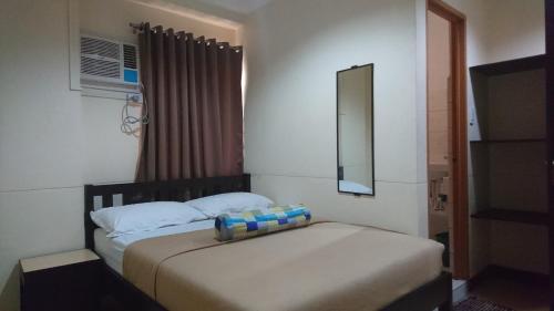 a bedroom with a bed with a mirror and a window at Calamba Pension Plaza in Calamba