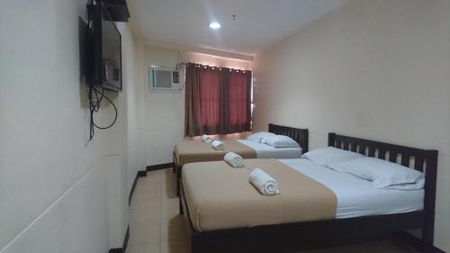 two beds in a small room with a television at Calamba Pension Plaza in Calamba