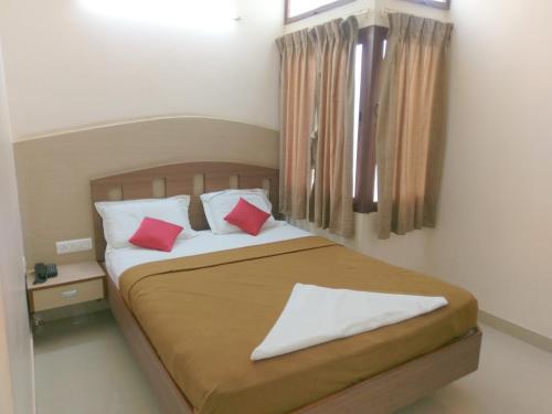 1 dormitorio con 1 cama con 2 almohadas rojas en Banyan Tree Comforts Mysore, en Mysore