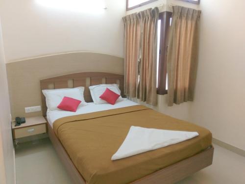 a bedroom with a bed with two red pillows at Banyan Tree Comforts Mysore in Mysore
