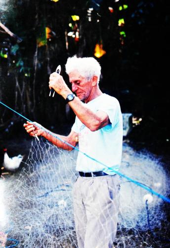 a man is holding a pole in front of a fence at Pousada da Rosa in Ilhabela