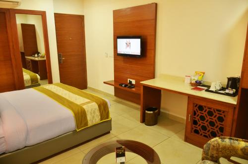 a hotel room with a bed and a desk and a tv at Mint Hotel Premia Chandigarh, Zirakpur in Chandīgarh
