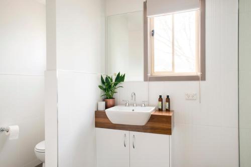 baño blanco con lavabo y ventana en The Peaks Halls Gap, en Halls Gap