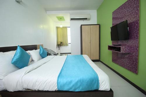 a bedroom with a large bed with blue and green walls at Hotel Hillton in Gandhinagar