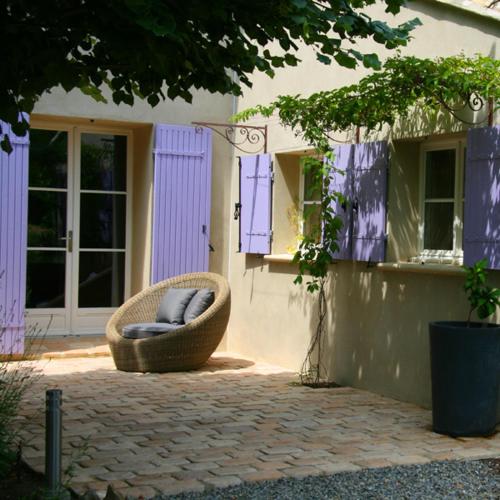 a wicker chair sitting in front of a house at Couleur Lavande in Le Thor