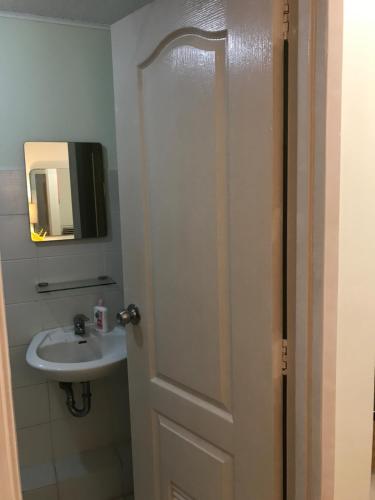 ein Badezimmer mit einem Waschbecken, einem Spiegel und einer Tür in der Unterkunft San Remo Oasis, Citta De Mari in Cebu City