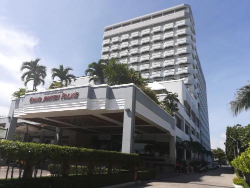 a large white building with palm trees in front of it at Grand Jomtien Palace Hotel - SHA Extra Plus in Jomtien Beach
