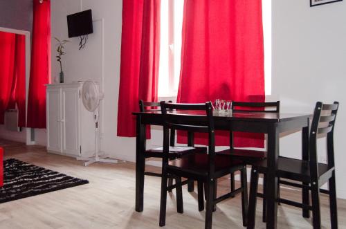 ein Esszimmer mit roten Vorhängen sowie einem Tisch und Stühlen in der Unterkunft L'Atrium in Béthune