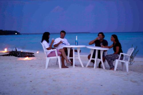 a group of people sitting at a table on the beach at Azoush Tourist Guesthouse in Fulhadhoo