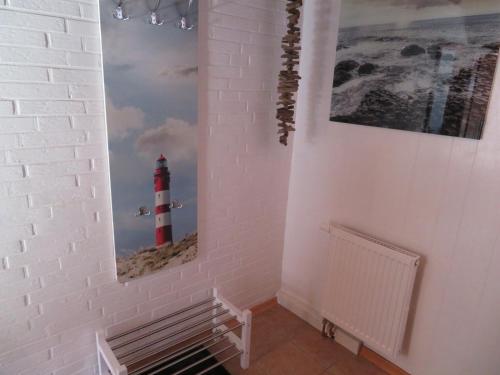 a white wall with a picture of a lighthouse at Ferienhäuser Seemannsgarn in Friedrichskoog-Spitz