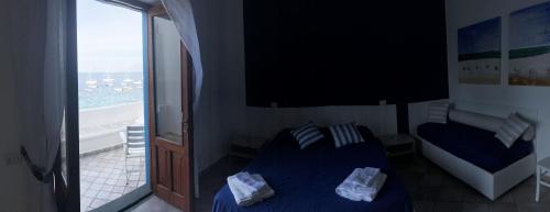 a bedroom with a blue bed and a window at Da Nino sul mare Filicudi in Filicudi